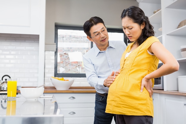 Прекрасный муж заботится о беременной жене с болями в спине на кухне