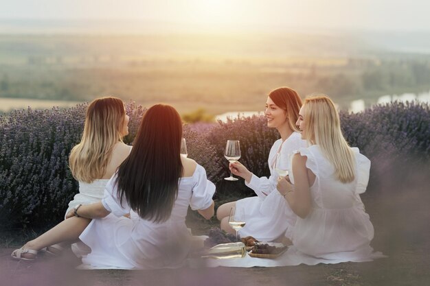 Foto signore adorabili che bevono vino nel campo viola lavanda al tramonto