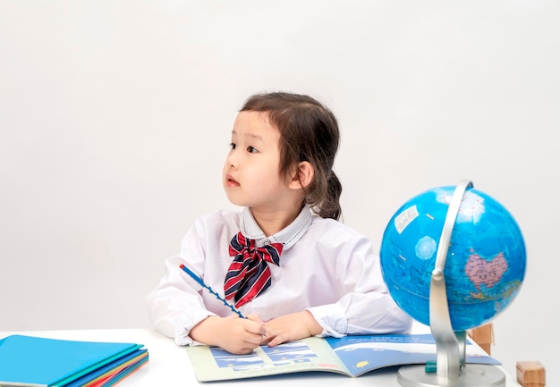 The lovely little girl is learning geography at her desk