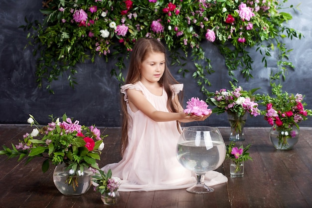 Lovely little girl playing with a bouquet of flowers in the vase