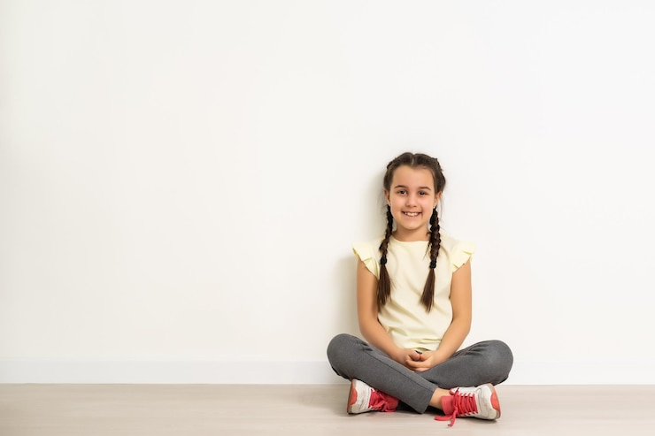 Photo lovely little girl sitting on the floor, isolated on white background.