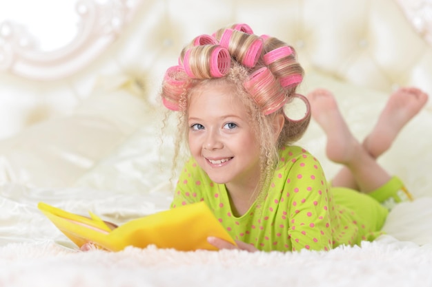 Lovely little girl with pink curlers reading