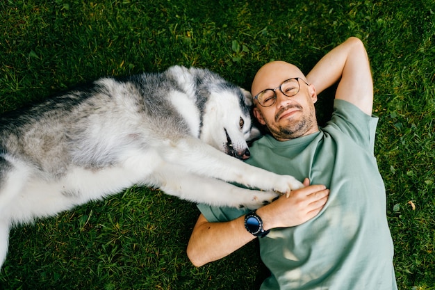 草の上に犬と一緒に横たわっている素敵な男