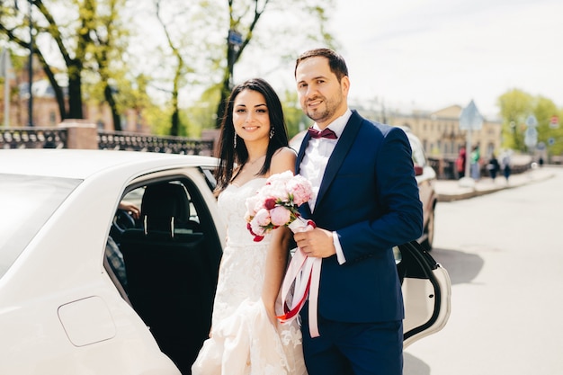 Lovely married couple stand next to each other near car