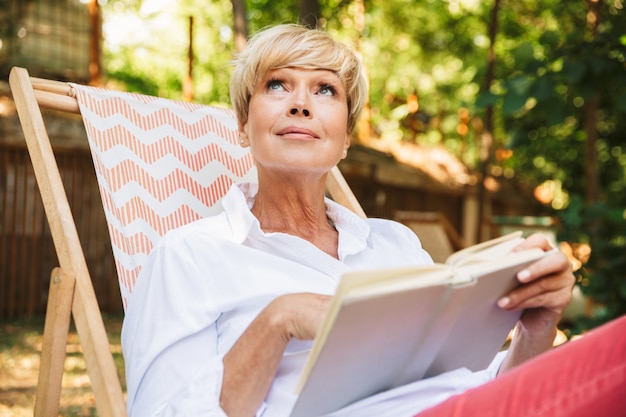Lovely mature woman reading a book while resting