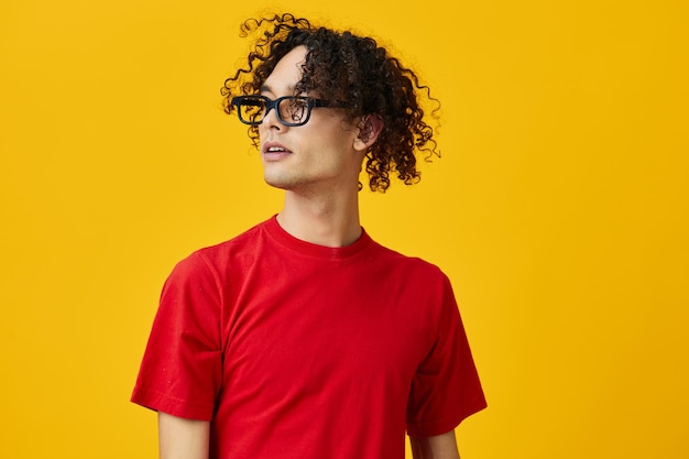 Lovely myopic young student man in red tshirt funny eyewear looks aside posing isolated on over yellow studio background the best offer with free place for advertising education college concept