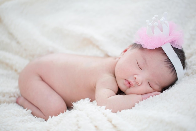 Lovely newborn Asian baby sleeping on furry blanket