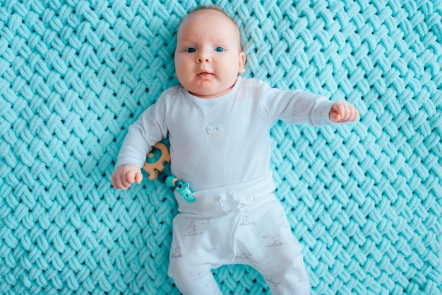 lovely newborn baby with blue eyes lying on bed.