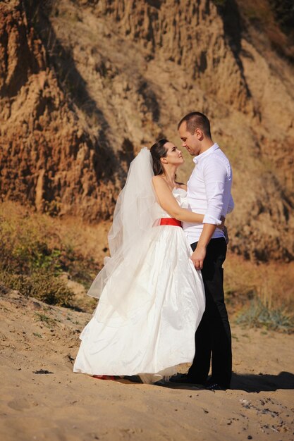 Lovely newlywed embrace at nature against mountain landscape