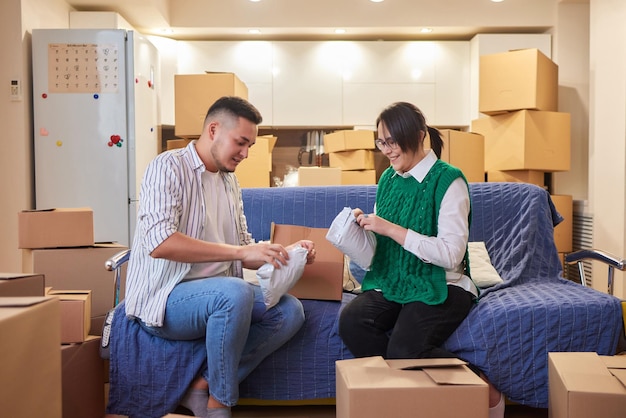 Lovely newlyweds with cardboard boxes moving in new apartment\
standing together on kitchen while man