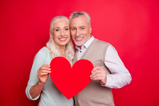 Lovely older couple posing together against the red wall