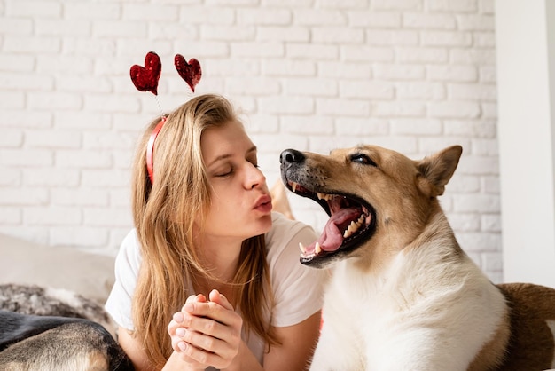 Lovely pet Young woman with her cute shepherd at home having fun and kissing funny picture