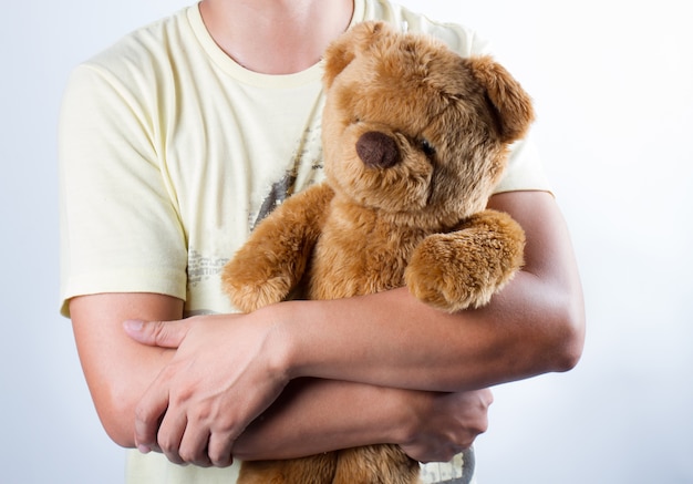 Lovely portrait of a young man cuddling a teddy bear