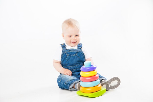 Lovely toddler in denim suit sitting and playing while smiling at camera isolated on white background.