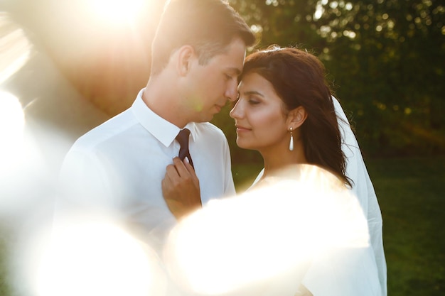 写真 日没時の素敵な結婚式のカップル花の花束と結婚式の服装の新郎新婦ロマンチックな