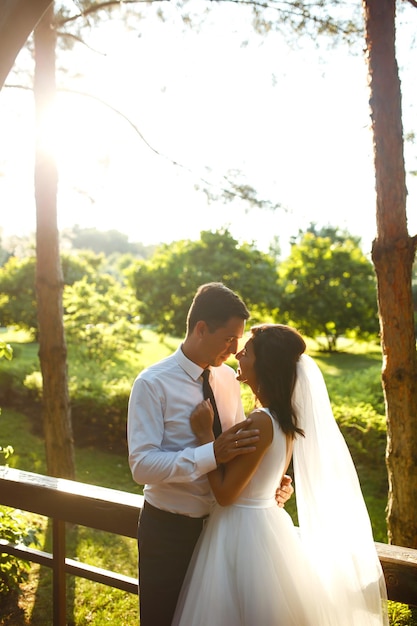 日没時の素敵な結婚式のカップル花の花束と結婚式の服装の新郎新婦ロマンチックな