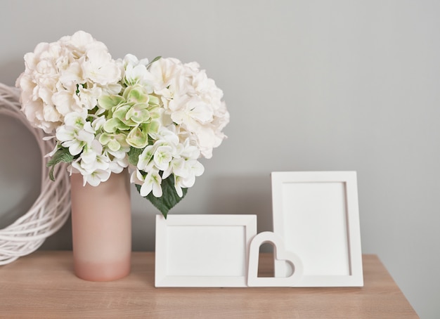 Photo lovely white photo frames on table with bouquet of white flowers