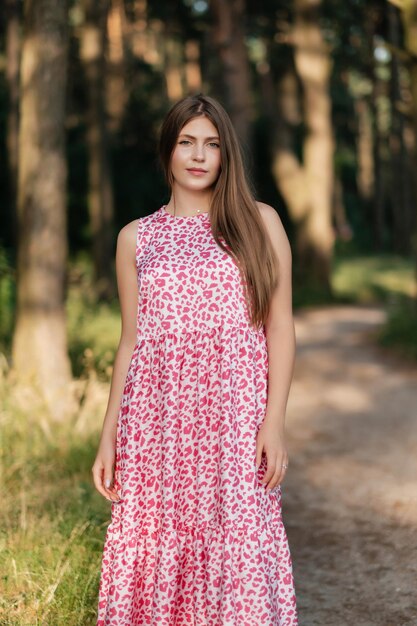 Bella donna in abito estivo rosa sulla strada forestale