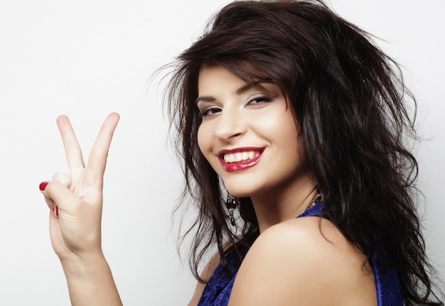 Lovely woman showing victory or peace sign over white background