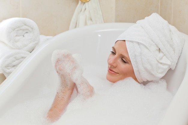 Lovely woman taking a bath with a towel on her head 