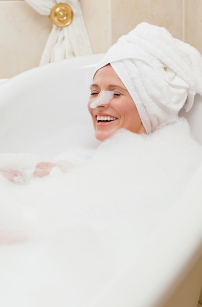 Lovely woman taking a bath with a towel on her head 