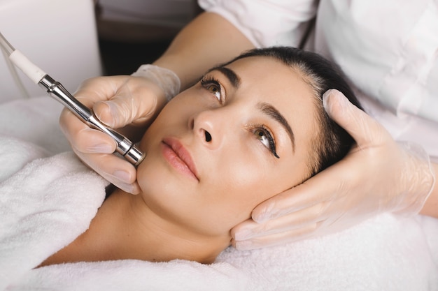 lovely  woman with black hair is waiting to finish her facial procedures at the spa salon