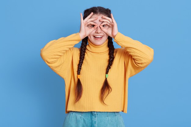 Lovely woman with dark hair, makes orbs with fingers, wears sweater and jeans