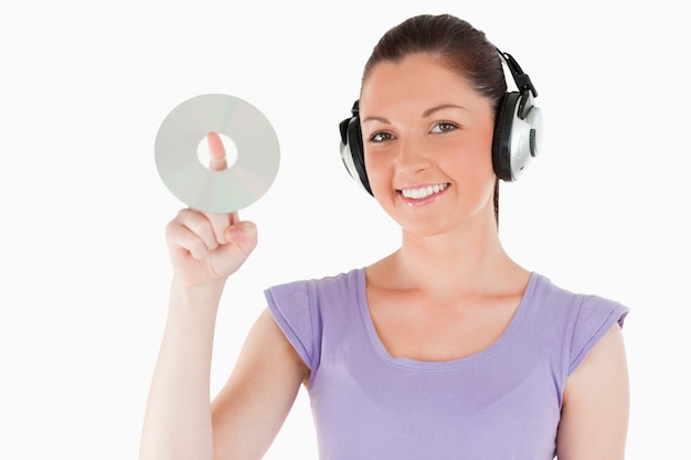 Lovely woman with headphones holding a CD while standing