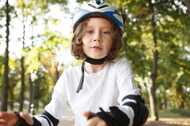 Lovely young boy wearing skate pads and helmet outdoors