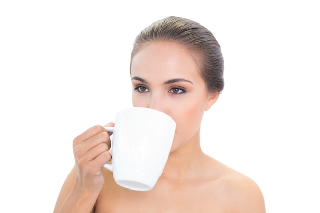 Lovely young brunette woman drinking out of a mug