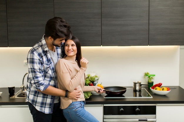 Photo lovely young couple preparing meal in the mdoern kitchen