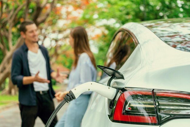 Lovely young couple recharging battery for electric car in autumn Exalt