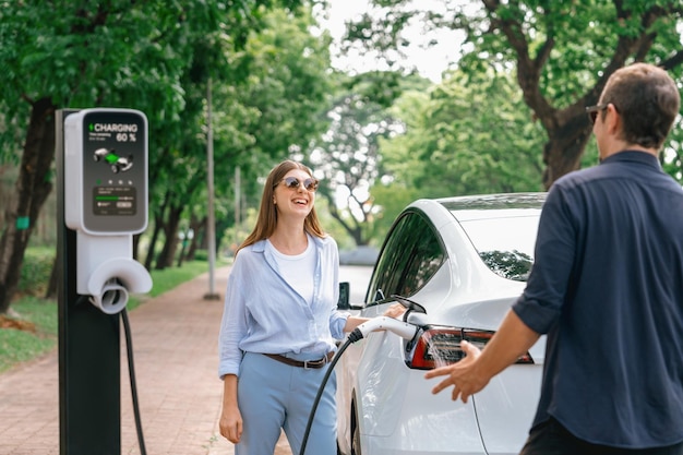 Photo lovely young couple recharging battery for electric car during road trip exalt