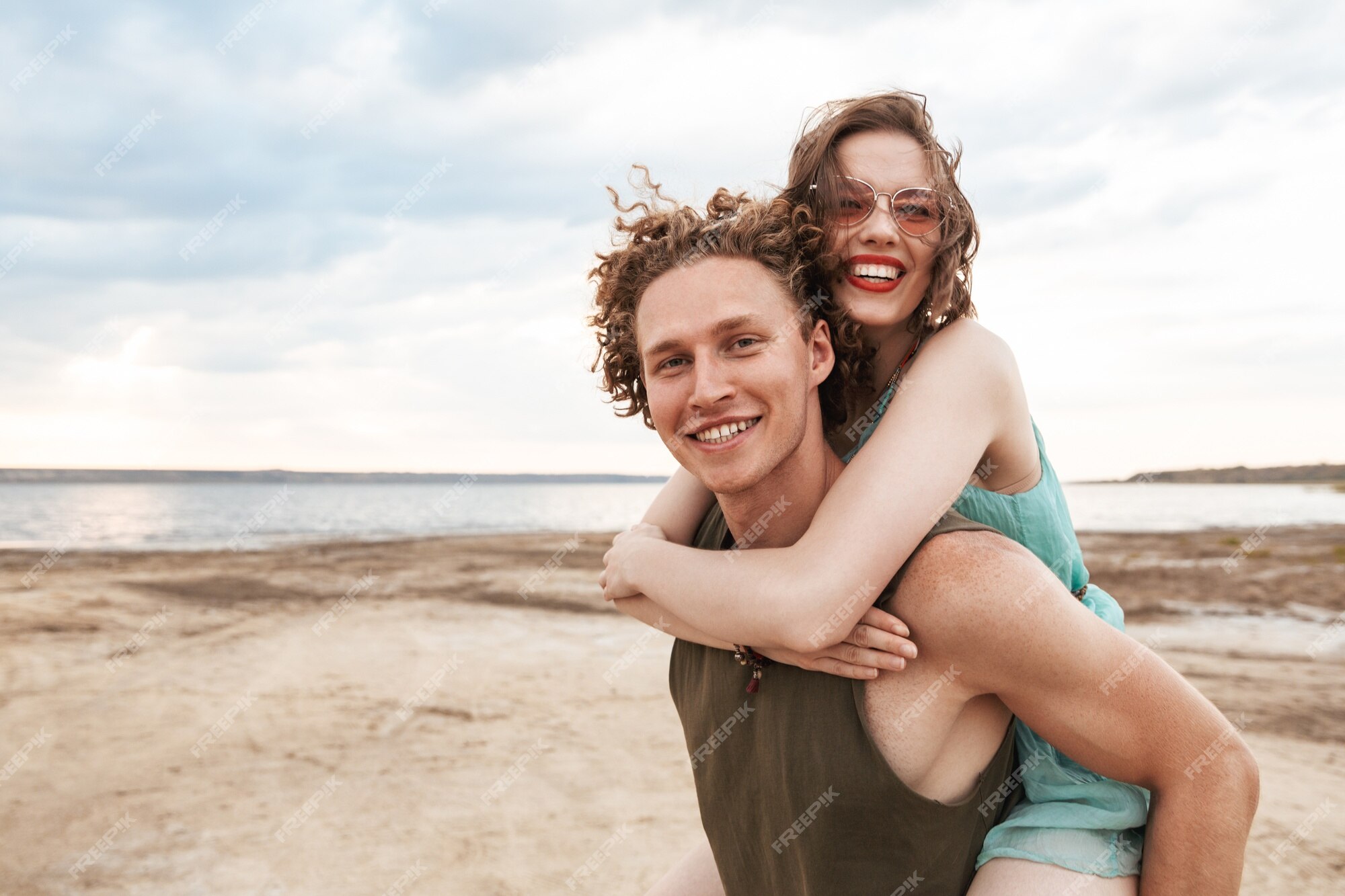 Lovely gay couple on piggyback ride at the beach. Stock Photo