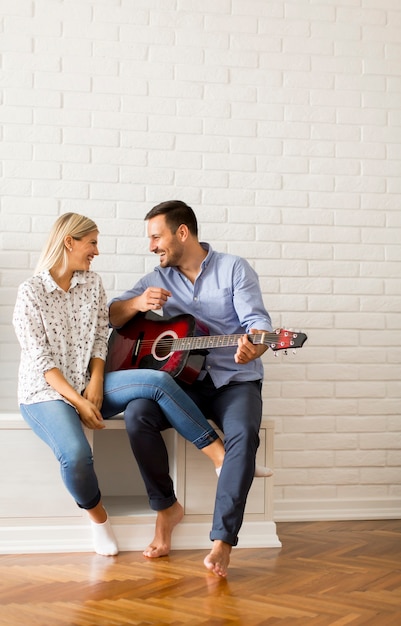 Lovely young couple with guitar in the room