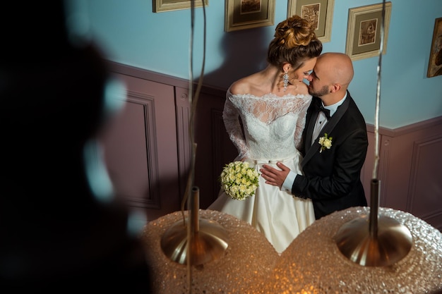 lovely young just married couple hugs on a ladder in wedding suits