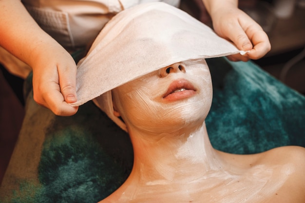 Lovely young woman doing facial skin care procedures in a spa center.