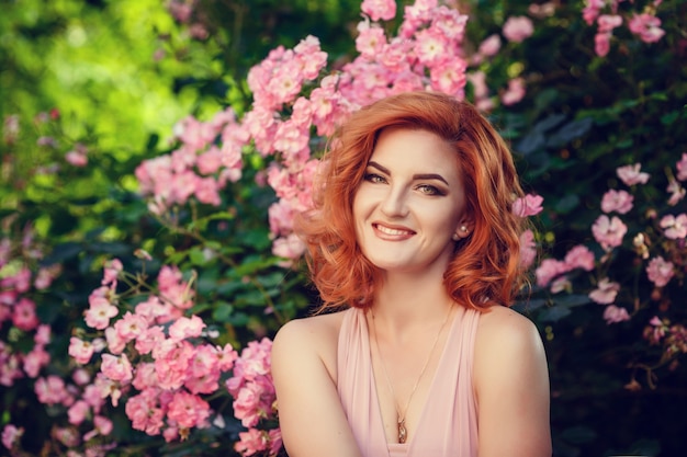 Lovely young woman in a pink dress and red hair, waiting for a date