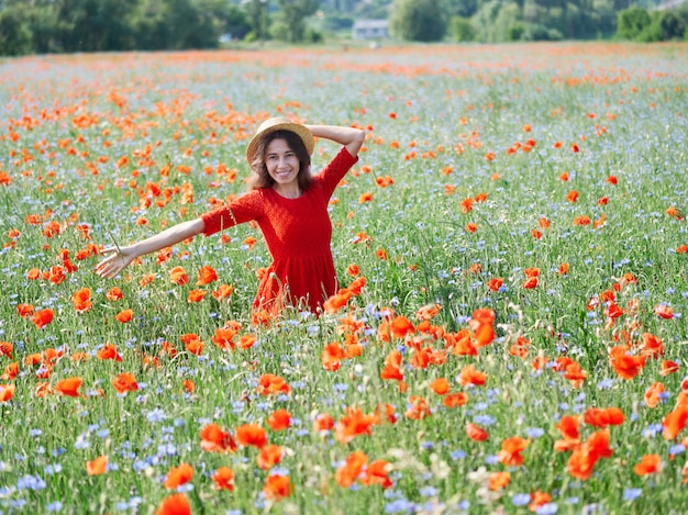 Lovely young woman in straw hat on poppy flower field