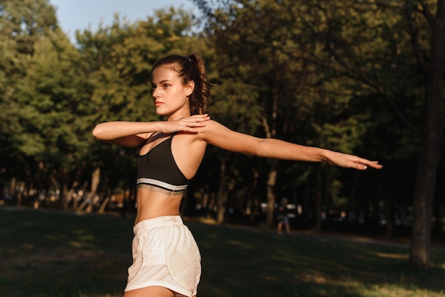 Lovely young woman stretches out in the park Morning exercises and outdoor sports