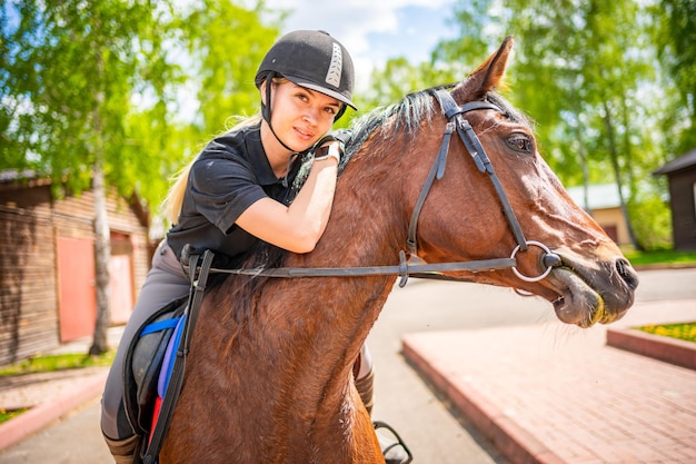 Lovely young woman wearing helmet riding her brown horse