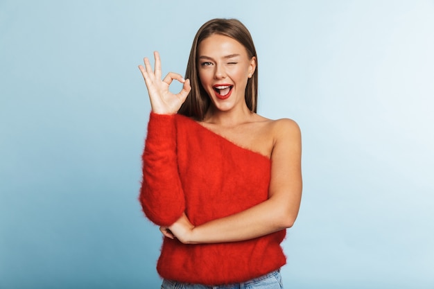 Lovely young woman wearing sweater showing ok gesture