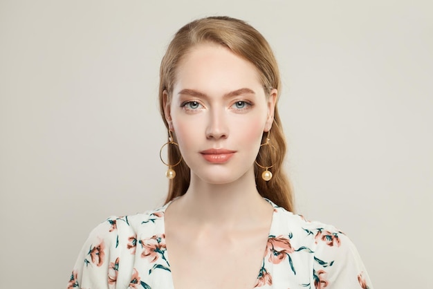 Lovely young woman with golden earrings with pearls on white