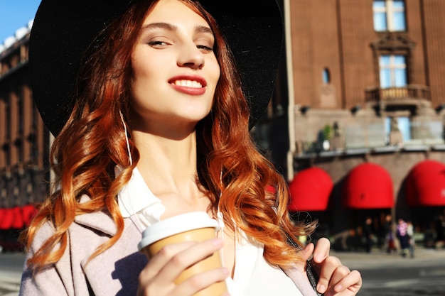 Lovely young woman with leather backpack drinks cappuccino