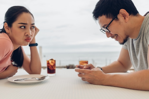 Lover couple is having a bad date at the restaurant on the beach.