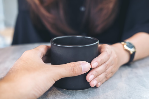 Lover couple touching a cup of coffee