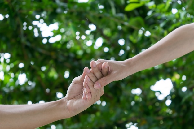 Lovers couple holding hands in a garden