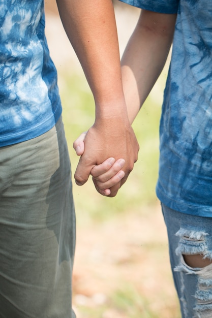 Foto amanti che si tengono per mano nella porta o nel parco