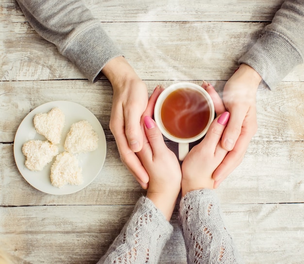 一杯のお茶を一緒に持っている恋人たち。セレクティブフォーカス