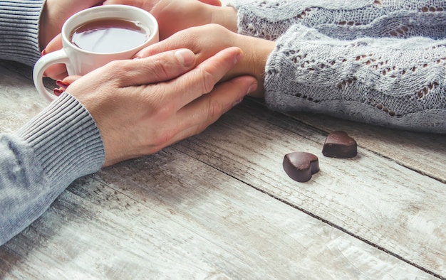 Lovers holding together a Cup of tea. Selective focus.